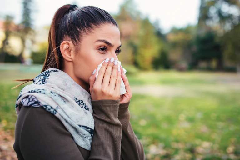 Woman who looks otherwise healthy blows her nose.