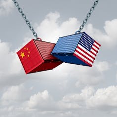Shipping containers with Chinese and American flags banging against each other.
