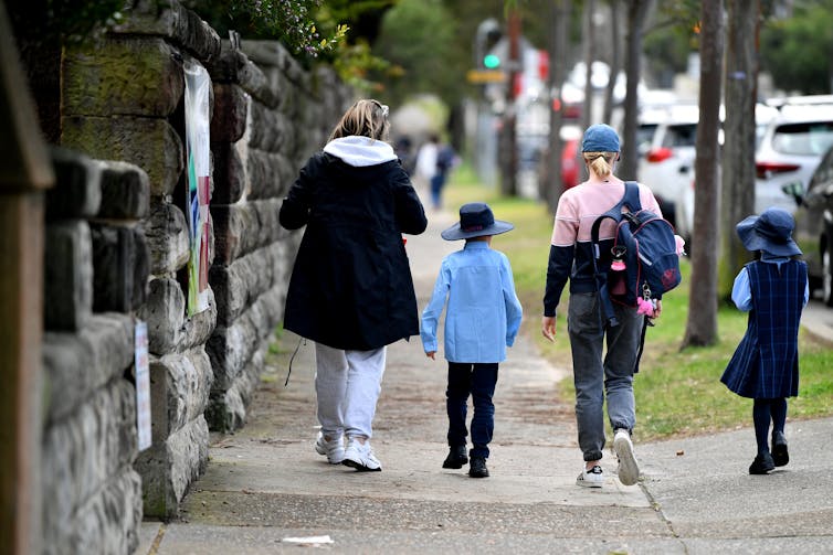 School children walk with parents down a street in Sydney.