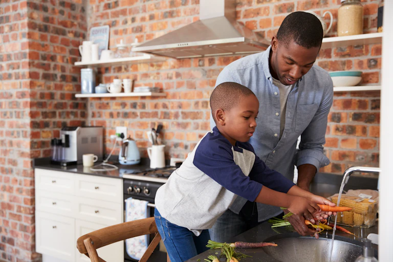 Boy helping man prepare food in kitchen