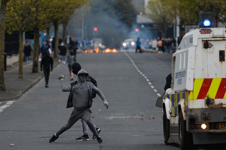 Loyalists throw a rock at police vehicles during unrest in Northern Ireland in April, 2021