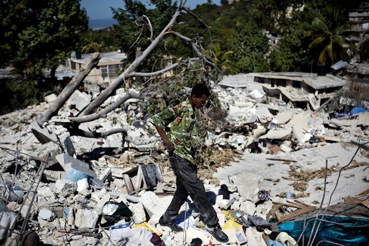 Un hombre camina sobre los restos de varias casas donde los cuerpos de las víctimas del terremoto aún no habían sido sacados de entre los escombros.