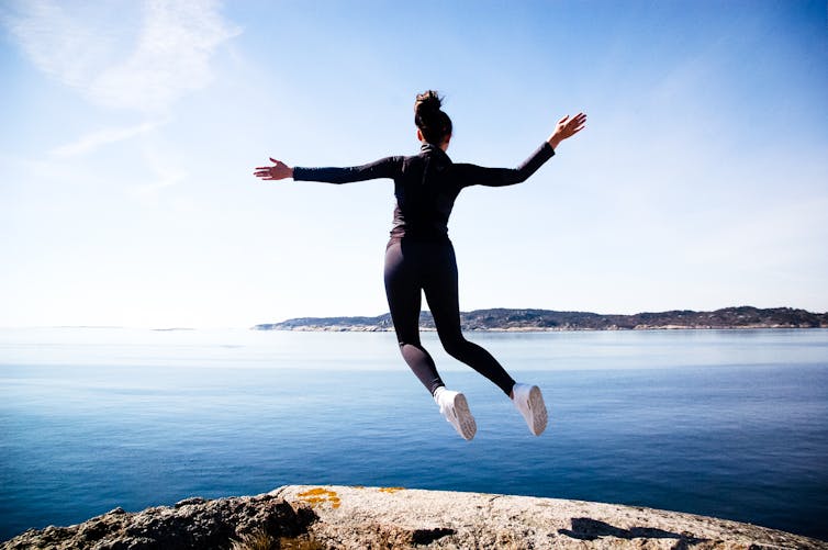 A woman appears to levitate near a cliff