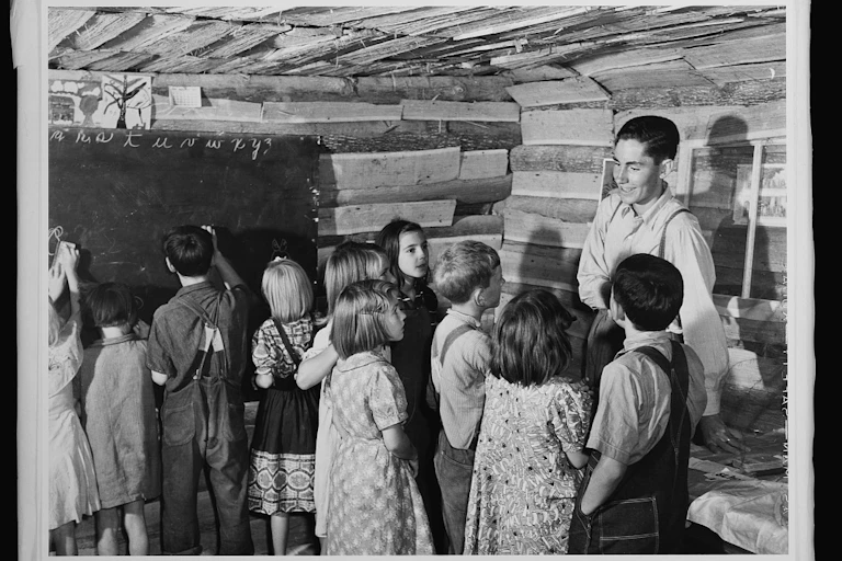 A teacher talking with students in a ramshackle one-room schoolhouse in 1940.