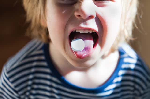 child with pill on tongue