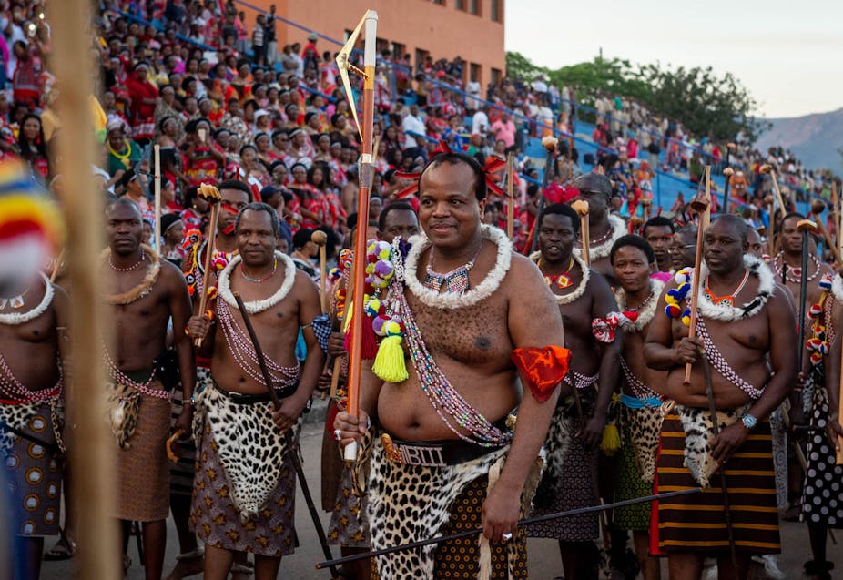 Men in traditional Swazi attire on a walkabout a stadium stadium.
