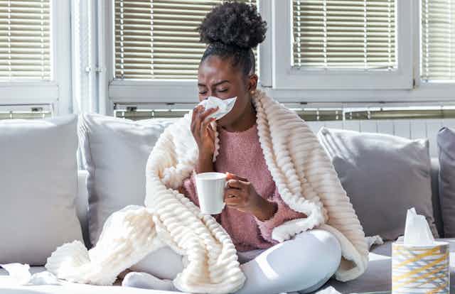 A woman with flu blowing her nose
