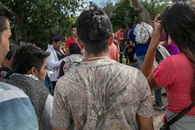 A dozen or so immigrant children, faces turned away from the camera, after coming across the Texas border from Mexico.