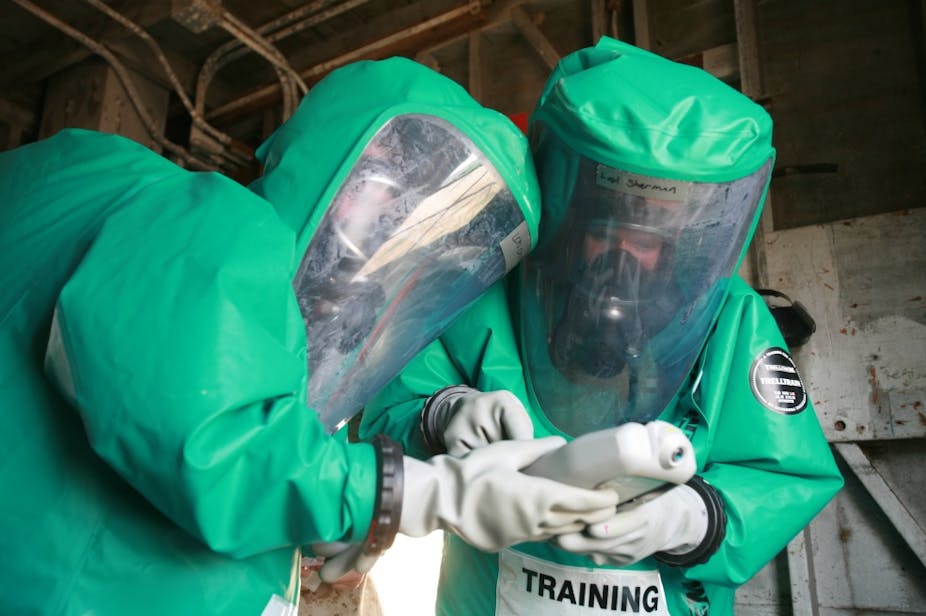 Two US Marines in green hazmat suits taking part in a bioweapon defense training