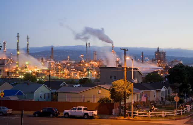 Homes next to a lit-up oil refinery in Wilmington, California.