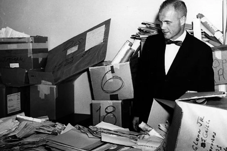 Glenn stands amid piles of mail