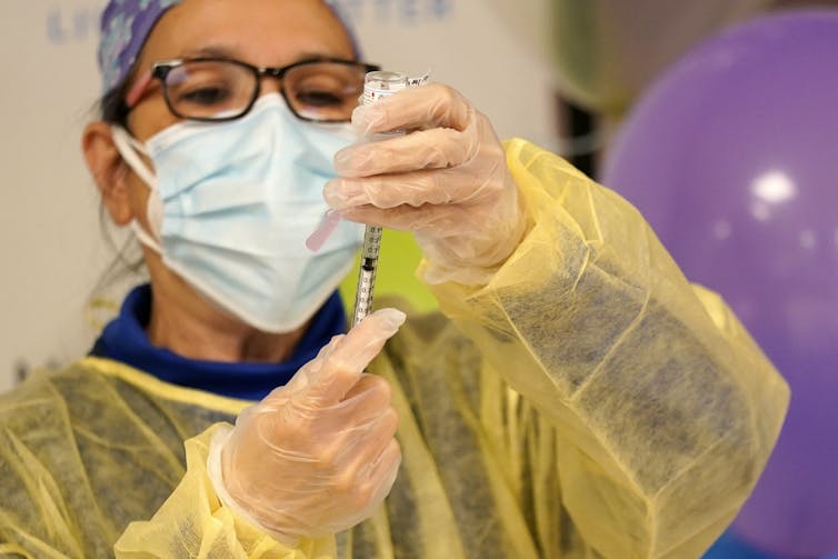 A medical worker drawing a vaccine dose into a syringe.