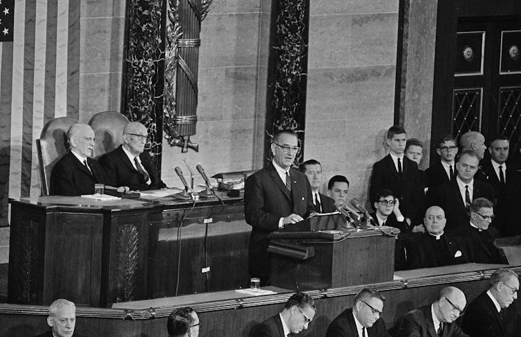President Lyndon B. Johnson delivers his State of the Union address to a joint session of Congress in the House of Representatives as lawmakers and other look on.