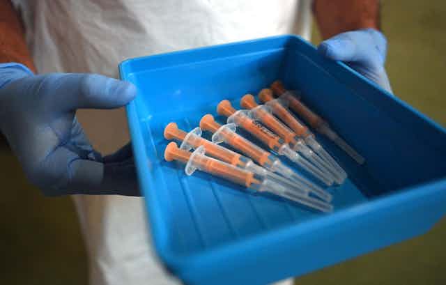 A nurse holding a tray full of syringes