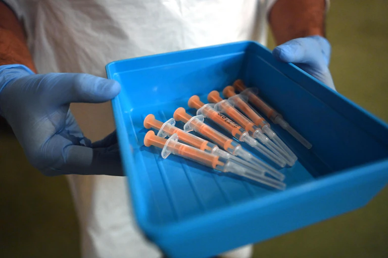 A nurse holding a tray full of syringes