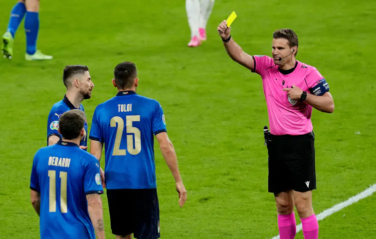 A footballer receives a yellow card.