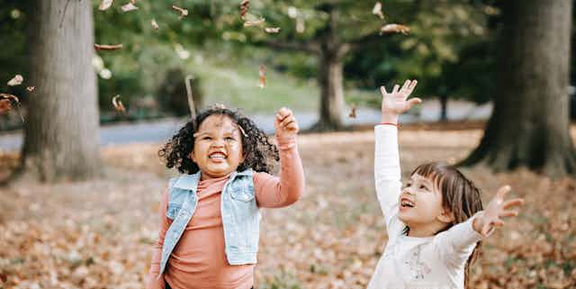 Two children throwing leaves in the air.