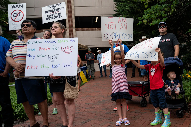 A group of protestors hold signs against the teaching of critical race theory in schools.