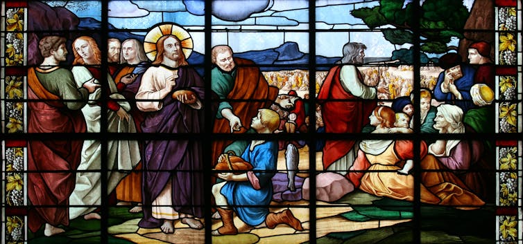 A stained-glass window depicting Jesus Christ feeding the 5,000.