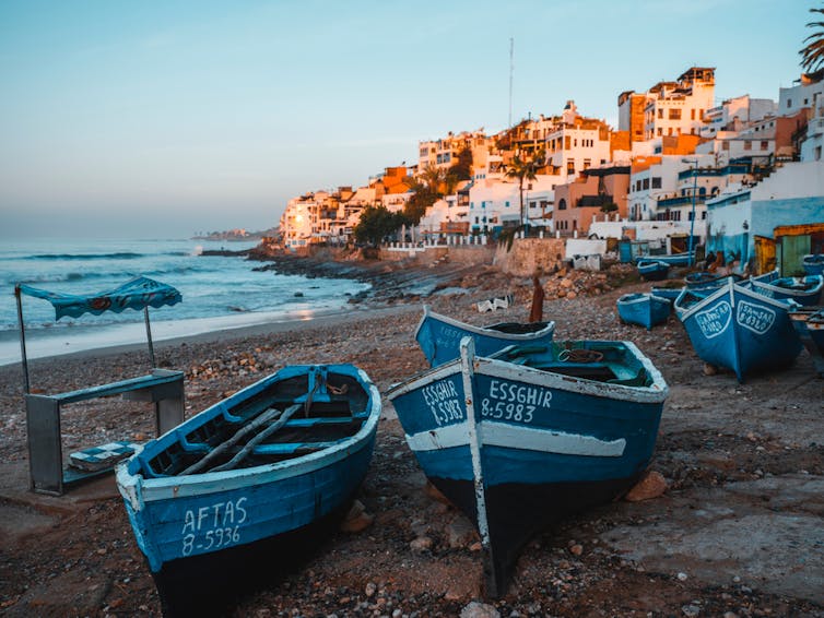 Traditional fishing boats line a beach in a coastal village of Morocco.