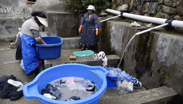 Dos mujeres de los pueblos indígenas de Bolivia lavan su ropa en un lavadero municipal con agua de lluvia en La Paz, el 12 de septiembre de 2019.