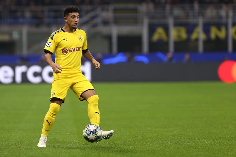 Footballer in yellow kit kicking a ball.