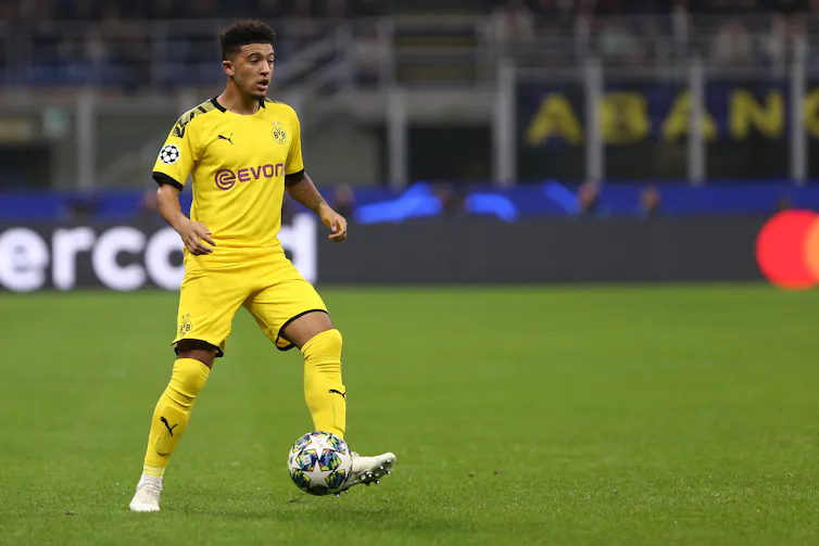 Footballer in yellow kit kicking a ball.
