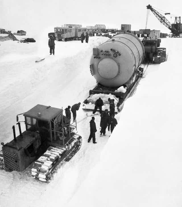 A large condenser on a sled is moved by tractor across the snow and ice