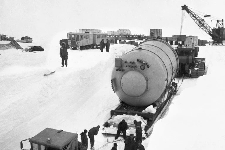 A large condenser on a sled is moved by tractor across the snow and ice