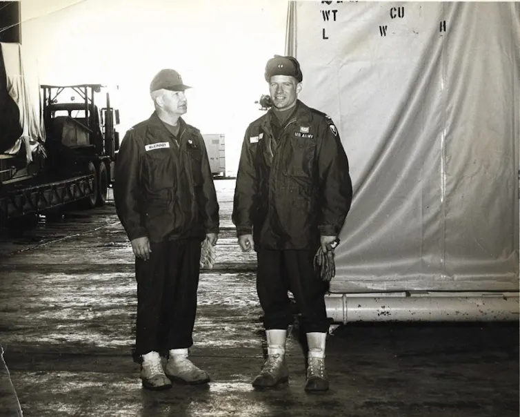 Two men in uniform standing in a hangar.