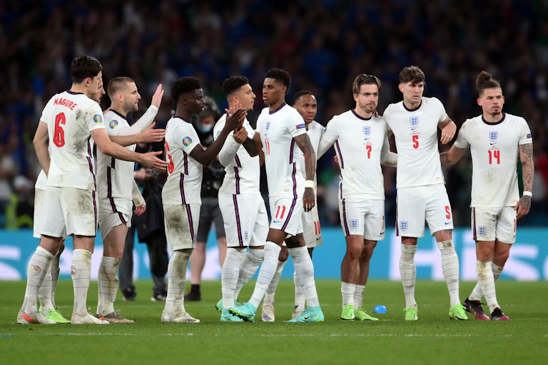 Row of England footballers on pitch high-fiving Marcus Rashford.