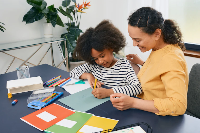 A child and an adult at a table with school supplies