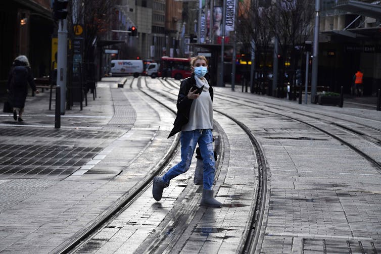 A woman crosses a deserted street in the Sydney CBD.