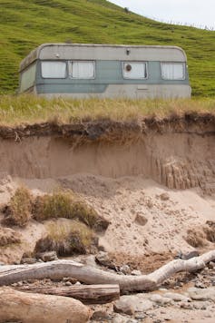 An eroded stretch of coast, with caravan parked.