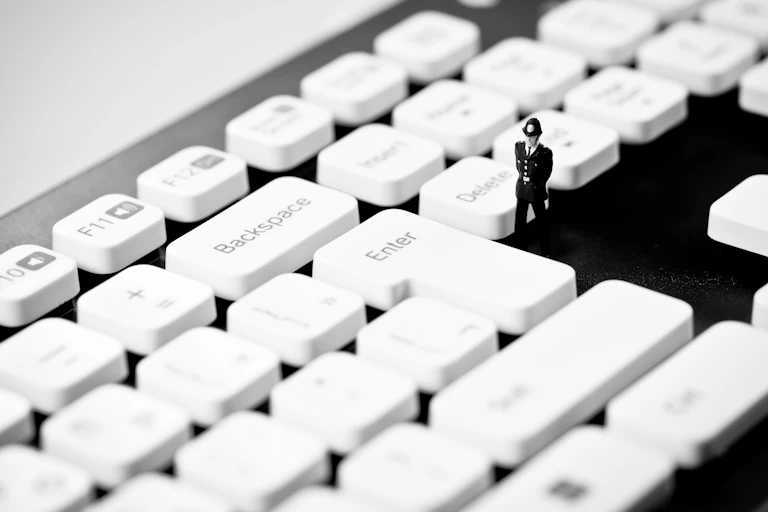 Miniature Police officer on top of computer keyboard.