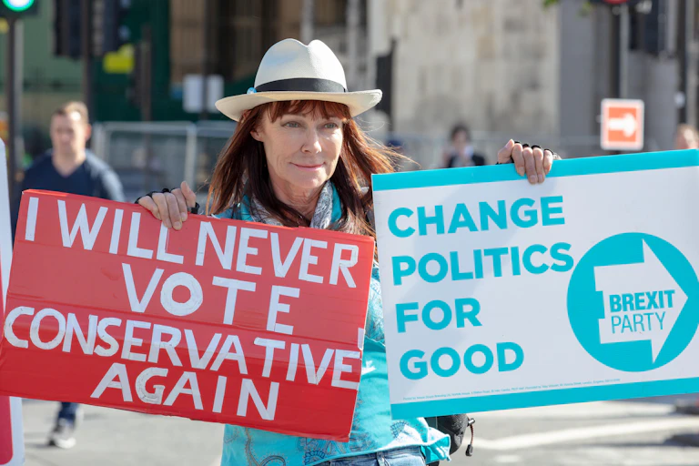 A woman holds two placards: One says "I will never vote conservative again," the other reads "Change politics for good: Brexit Party
