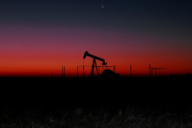 A machine is silhouetted against a sunset