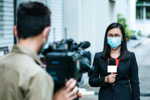 Journalist and cameraman shooting outdoor news update while wearing mask prevent Covid-19 or coronavirus quarantine pandemic.