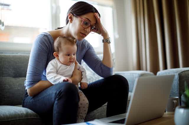 Mother holds baby in lap while working on computer