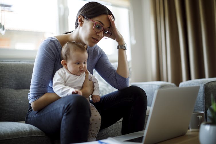 woman looking stressed while holding baby