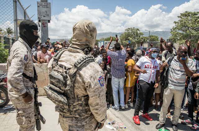Police look on as Haitian citizens gather.