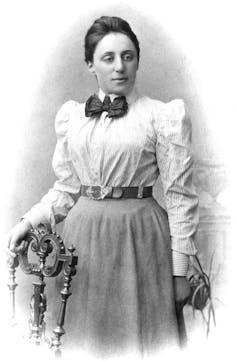 A black and white portrait of a young Emmy Noether in a shirt and a skirt.