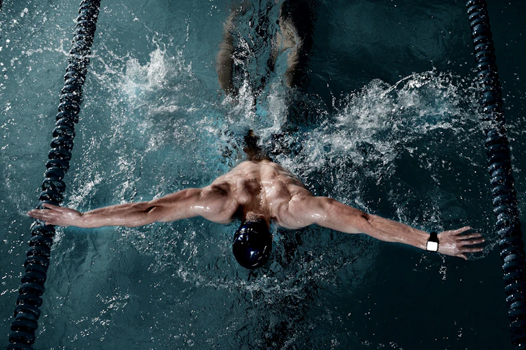A swimmer wearing a watch is doing the butterfly stroke