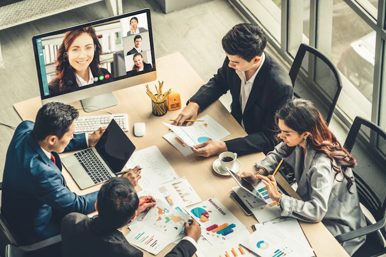 Business meeting combining participants seated at a table and in an online video call
