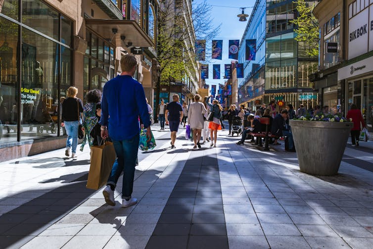 People shop on a sunny Stockholm street.