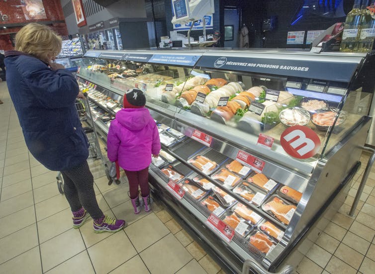 A customer and a little girl look at the seafood counter at a Metro store in Ste-Therese, Que