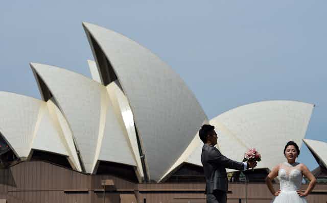 Bride and groom pose in front of the Sydney Opera House.