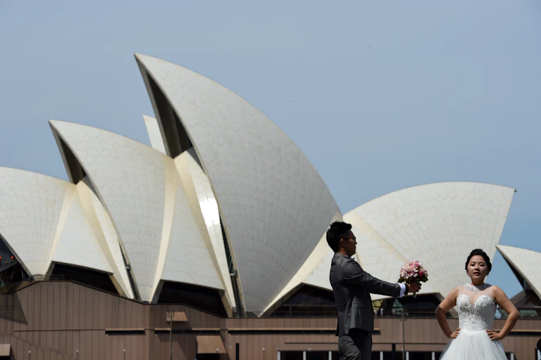 Bride and groom pose in front of the Sydney Opera House.