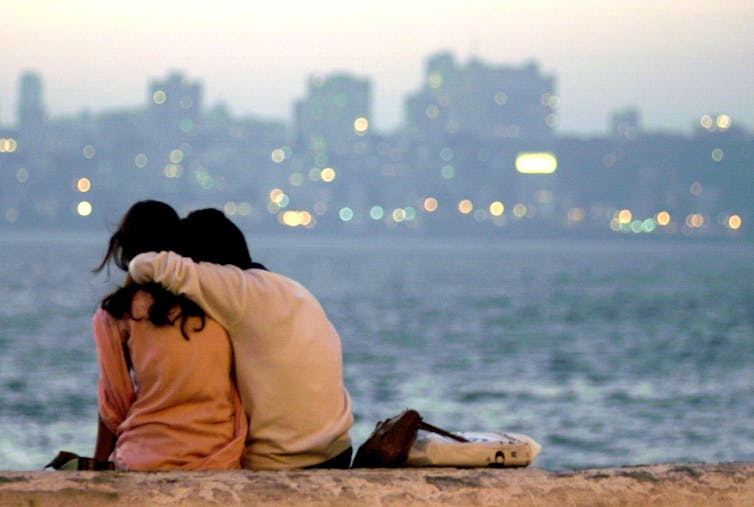 Couple hug as they look at a river view.