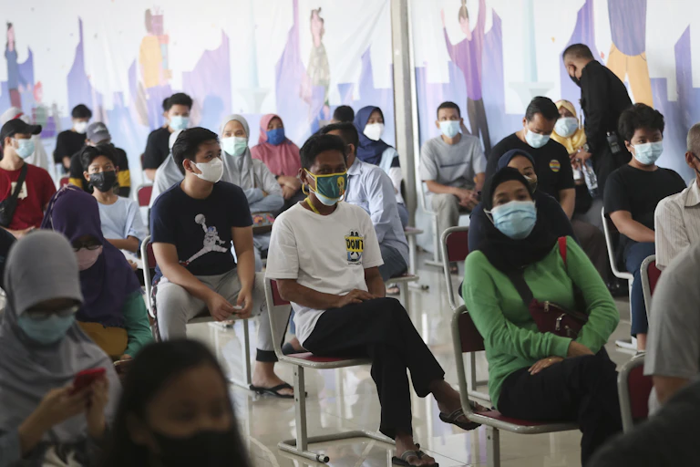 People in Indonesia sit on chairs, waiting for vaccines.